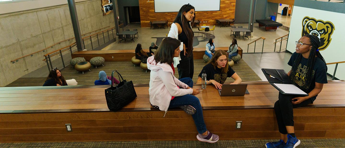 Oakland University students seated together on a ledge in the Oakland Center.